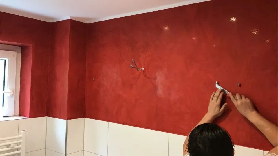 Person steht an roter Wand in einem Zimmer
